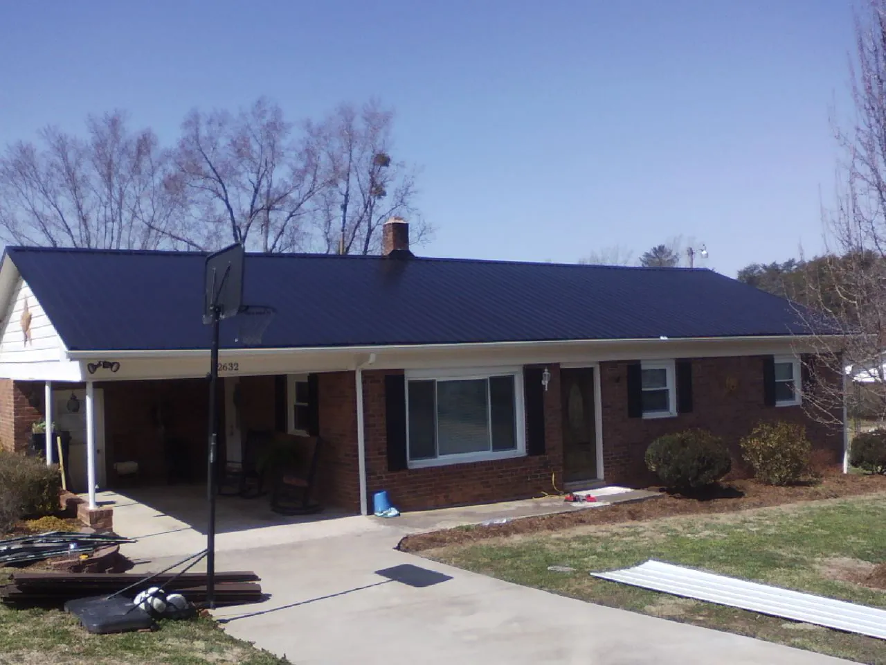 Finished dark blue metal roof on a brick ranch with a carport in Virginia Beach