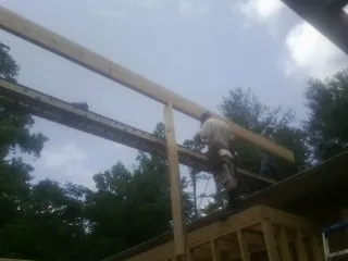 Carpenter setting a ridge beam over a new addition frame — Ice Dam Removal by Roofing Brothers in Virginia Beach