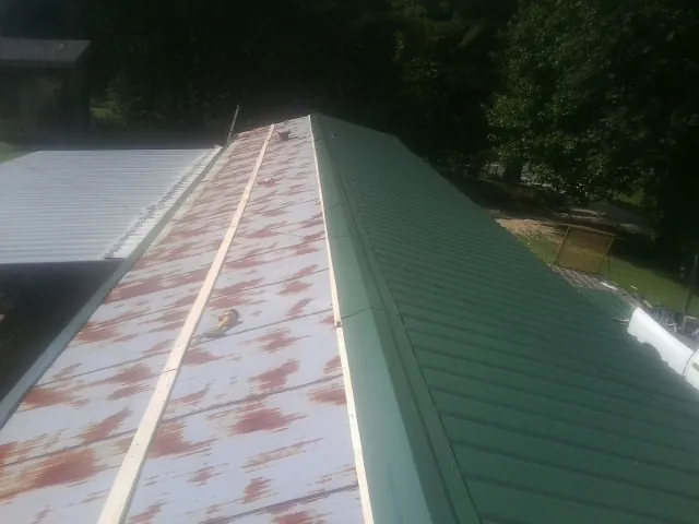 Old rusted panels beside newly installed green metal roofing — Wind Damage Roof Repair by Roofing Brothers in Virginia Beach