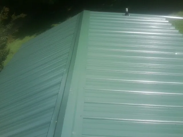 New green metal panels meeting at the ridge of a roof — Flat Roof Repair work by our crew in Virginia Beach