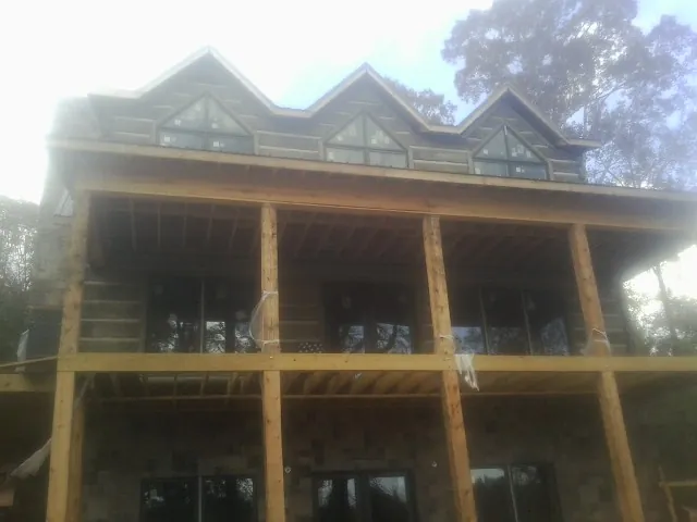 Dormers and porch framing on a large log home under construction — Roof Coating work by our crew in Virginia Beach