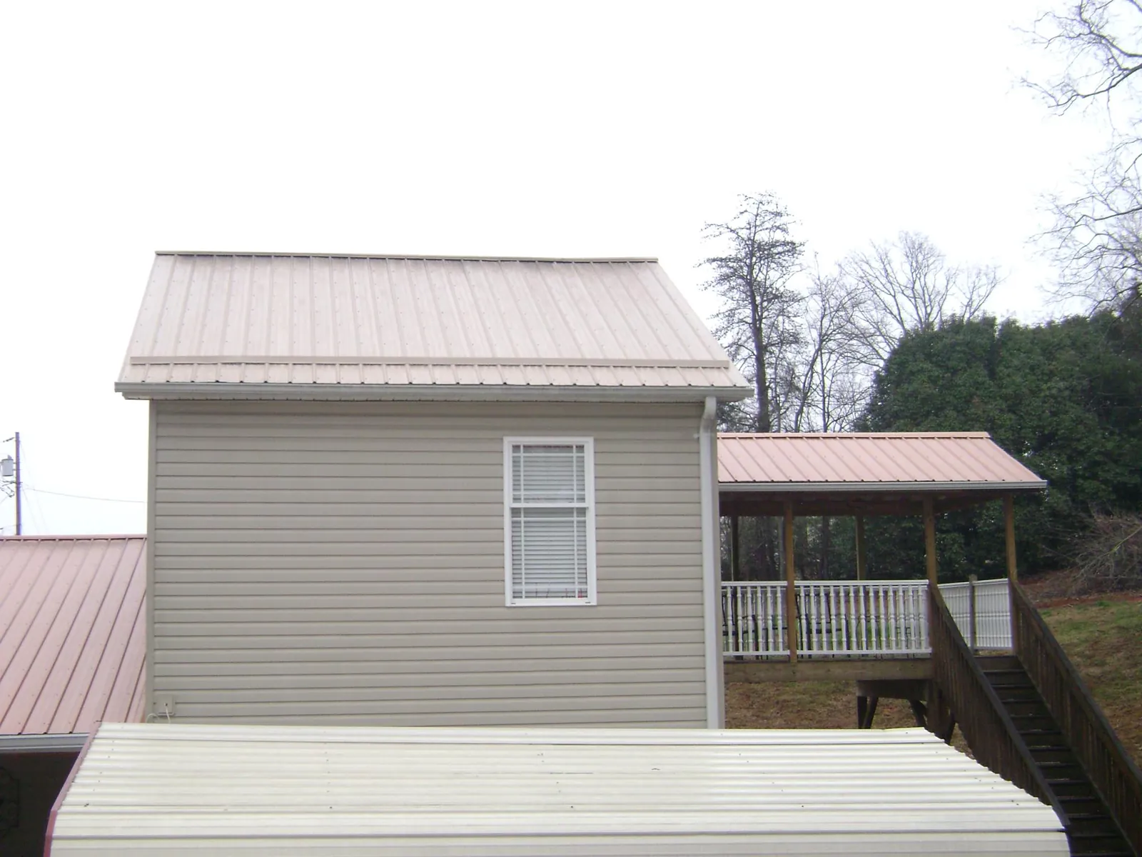 Tan metal roofs on a two story addition and attached porch, from a Roof Replacement job in Virginia Beach