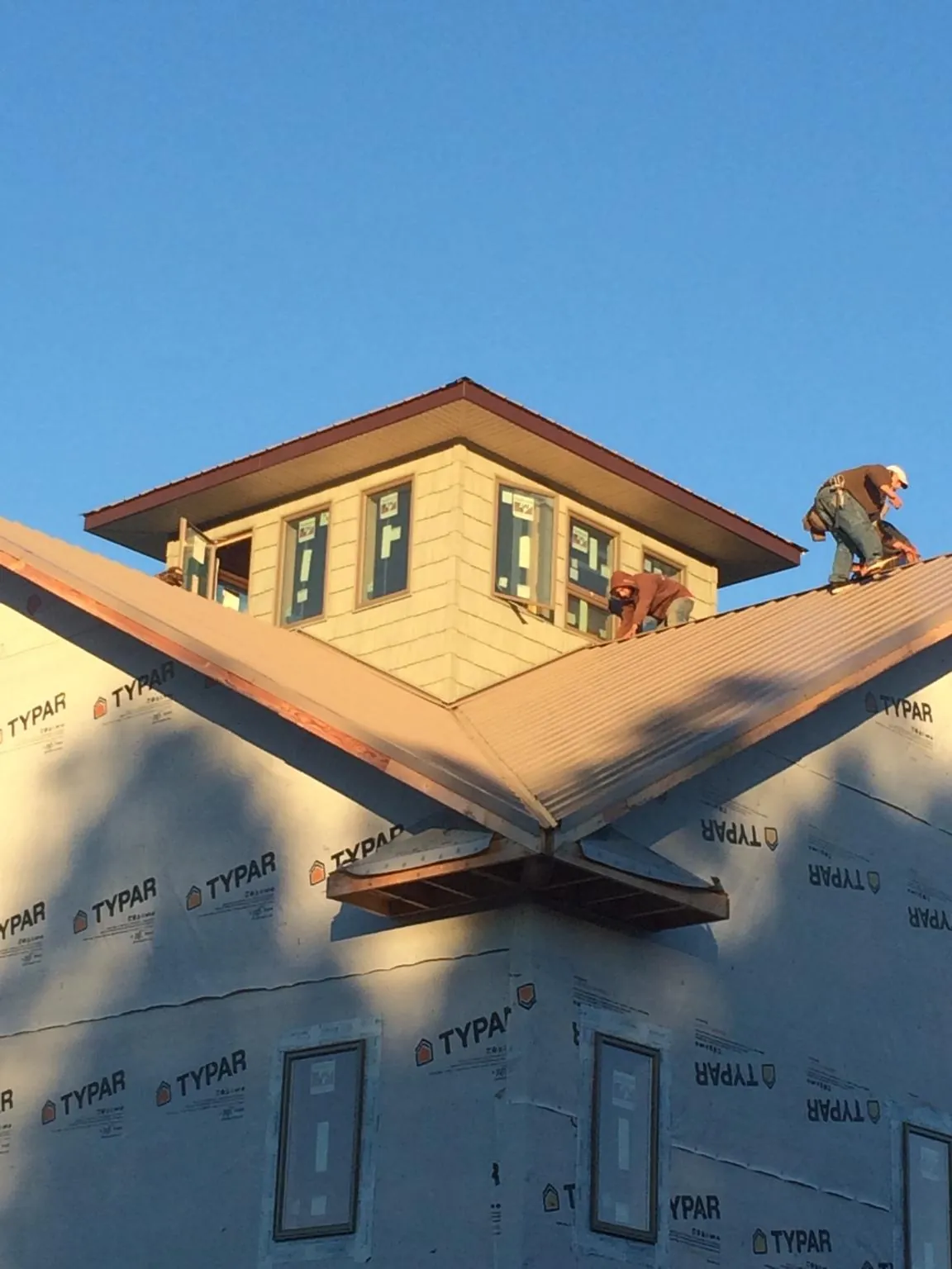 Roofers working around a rooftop cupola on a new metal roof at sunset — Roof Waterproofing in Virginia Beach by Roofing Brothers